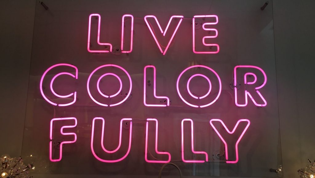 Neon sign displaying the words 'live color fully'.